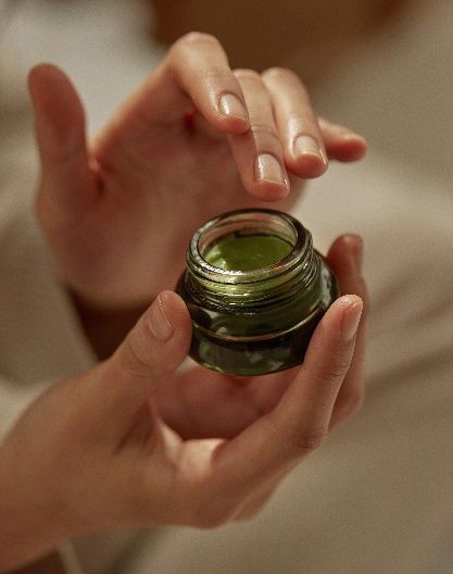 Mains tenant un pot de soin naturel ouvert